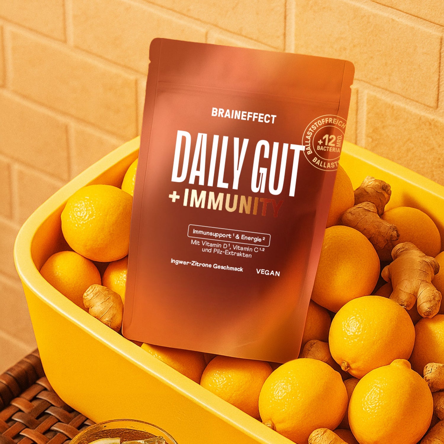 Eine gelbe Schüssel mit frischen Zitronen und Ingwer, im Vordergrund die BRAINEFFECT Daily Gut + Immunity Verpackung.