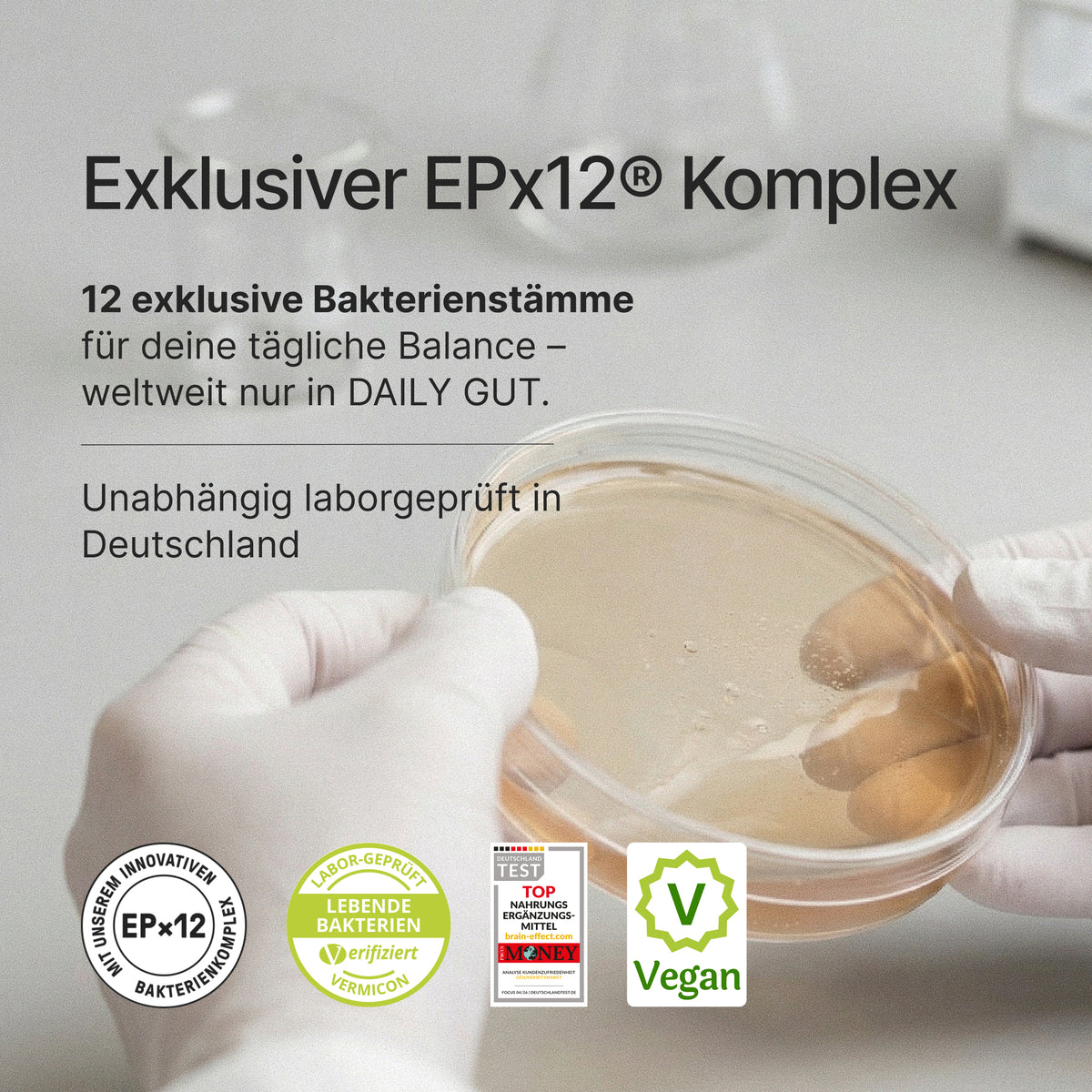 Des mains gantées de blanc tiennent une boîte de Pétri avec du texte : Exklusiver EPx12® Komplex 12 exklusive Bakterienstämme für deine tägliche Balance – weltweit nur in DAILY GUT.