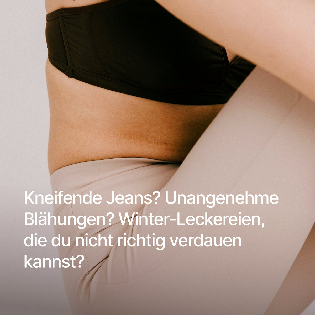 Ausschnitt einer Frau in schwarzem Sport-BH und heller Leggings mit dem Text "Kneifende Jeans? Unangenehme Blähungen? Winter-Leckereien, die du nicht richtig verdauen kannst?".