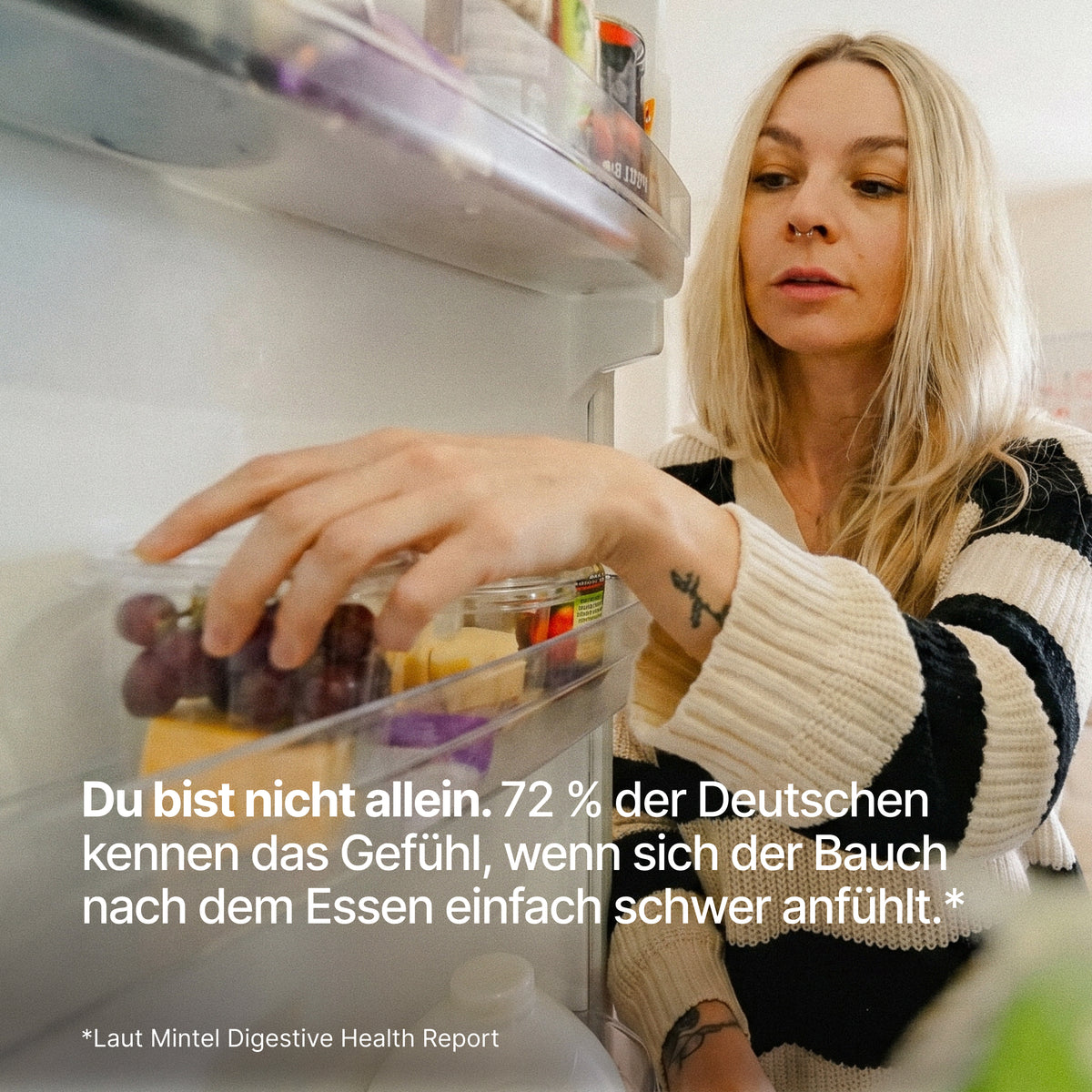 Eine blondhaarige Frau im gestreiften Pullover greift in den geöffneten Kühlschrank neben dem Text "Du bist nicht allein. 72 % der Deutschen kennen das Gefühl, wenn sich der Bauch nach dem Essen einfach schwer anfühlt.*"