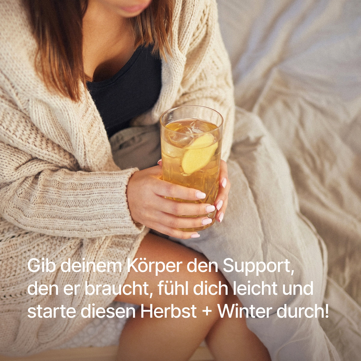 "Gib deinem Körper den Support, den er braucht, fühl dich leicht und starte diesen Herbst + Winter durch!" Person im Strickcardigan hält ein Glas mit Kaltgetränk und Ingwerscheibe.