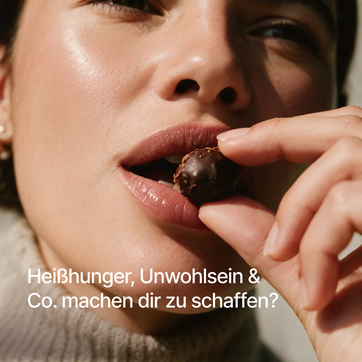 Eine Frau hält eine kleine Schokoladenkugel an den Mund im Nahaufnahmebild mit dem Text "Heißhunger, Unwohlsein & Co. machen dir zu schaffen?"