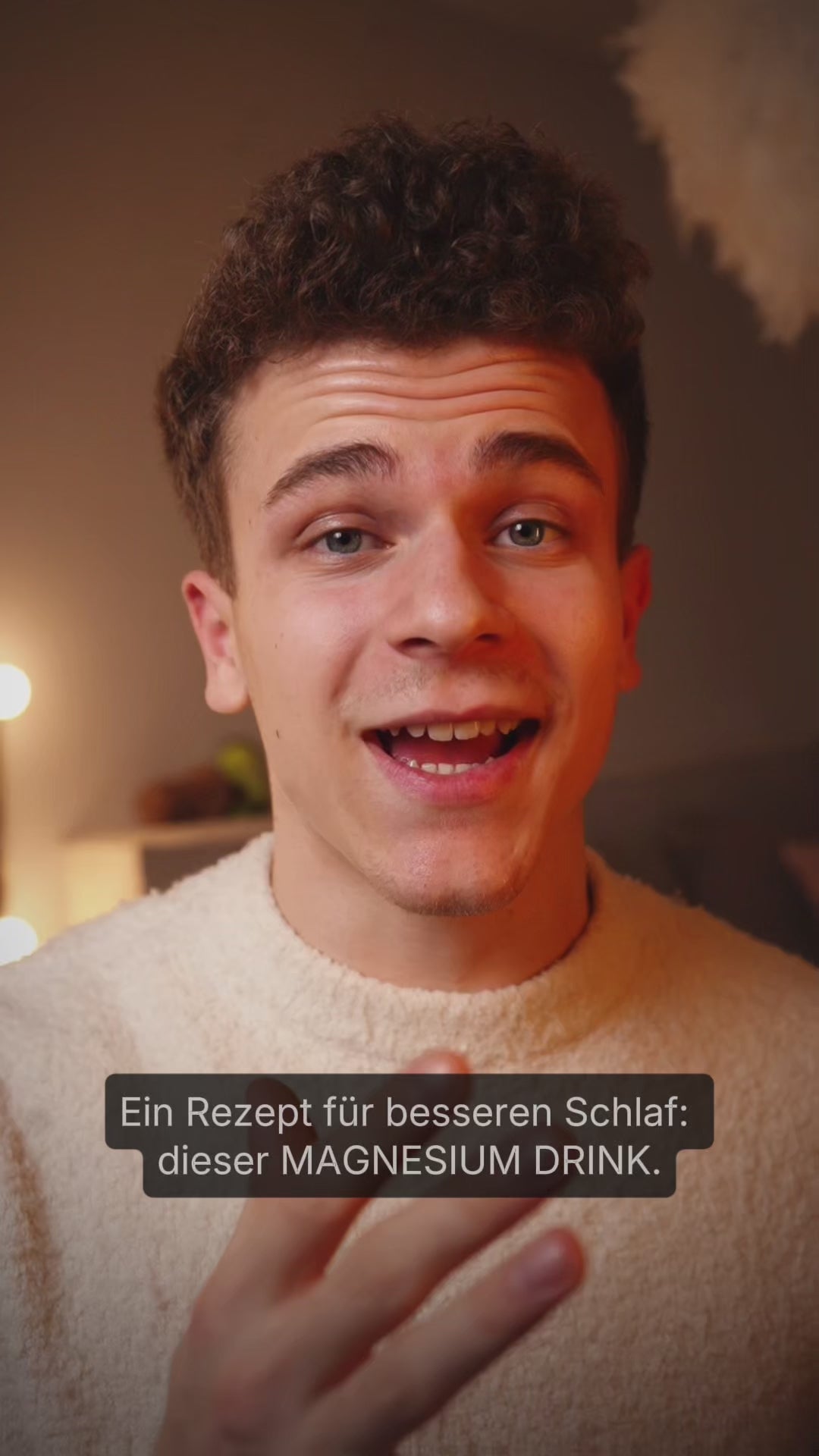 Video laden: Junge mit dunklen Locken und hellem Pullover spricht vor der Kamera mit dem eingeblendeten Text "Ein Rezept für besseren Schlaf: dieser MAGNESIUM DRINK."