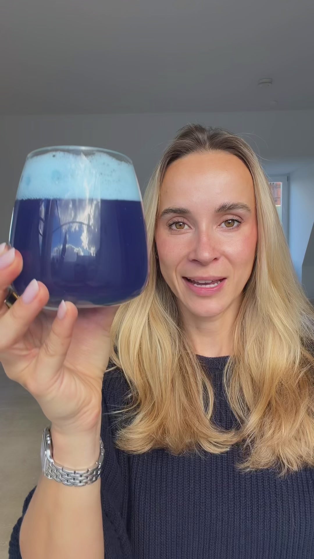 Video laden: Eine blonde Frau hält ein Glas mit einem tiefblauen Getränk und heller Schaumkrone in die Kamera.