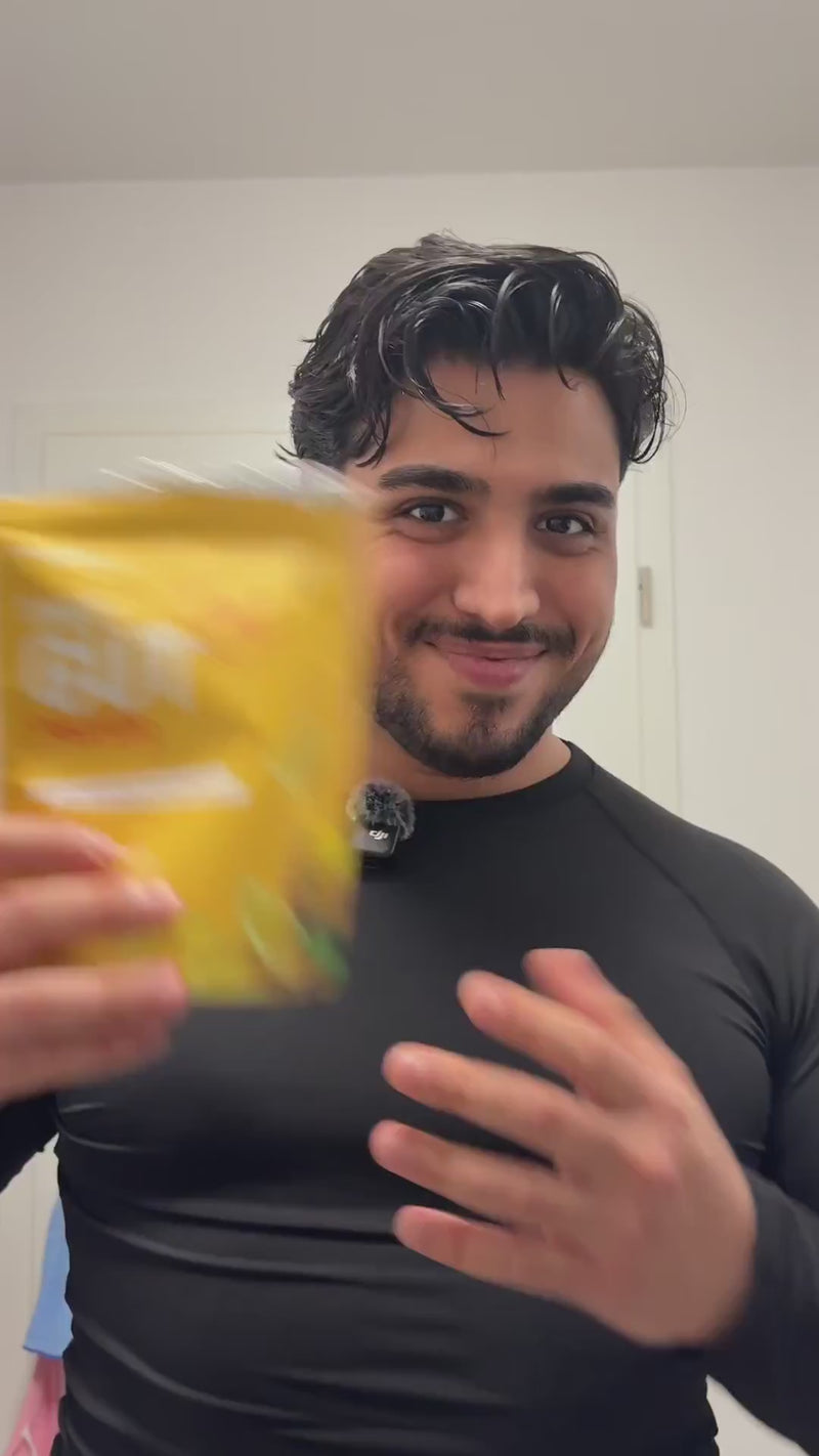 Ein Mann mit schwarzem Langarmshirt hält eine gelbe BRAINEFFECT Daily Gut Verpackung in die Kamera.